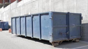 Metal durable blue industrial trash bin for outdoor trash at construction site. Large waste basket for household or industrial waste. A pile of waste. video