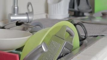 gli utensili da cucina nel lavabo devono essere lavati. una pila di piatti sporchi nel lavello della cucina. gli utensili da cucina devono essere lavati. concetto di compiti a casa. video