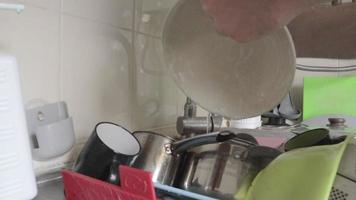 manos masculinas de primer plano lavando un plato sucio y grasiento en el fregadero de la cocina con un paño de espuma. espuma de jabón y burbujas. el hombre limpia y limpia el plato con una esponja verde. video