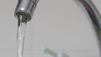close-up de beber água da torneira fluindo de uma torneira. projetar uma torneira na cozinha ou banheiro. o conceito de economia de água e consumo de água, tarifa e preço da água. video