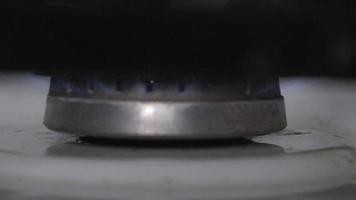 Light the gas stove by hand with a stove lighter. Kitchen gas stove with burning propane fire. A man's hand turns on a gas burner, and natural gas ignites with a blue flame.