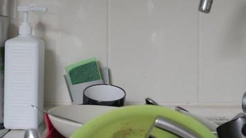 gli utensili da cucina nel lavabo devono essere lavati. una pila di piatti sporchi nel lavello della cucina. gli utensili da cucina devono essere lavati. concetto di compiti a casa. video