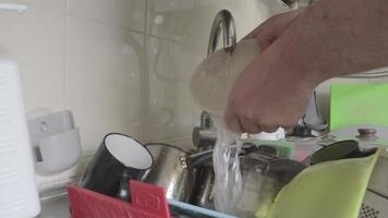 detailopname mannetje handen het wassen een vuil en vettig bord in de keuken wastafel met een schuim washandje. zeep schuim en bubbels. de Mens reinigt en reinigt de bord met een groen spons. video