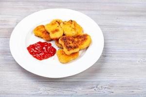 nuggets de pollo frito con ketchup en tablero gris foto