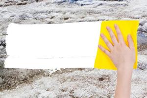 hand deletes melting snow by yellow rag photo