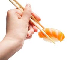 wooden chopsticks hold nigiri sushi with salmon photo