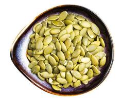 peeled pumpkin seeds in ceramic bowl isolated photo