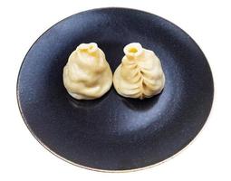 two steamed Buuz dumplings on dark plate isolated photo