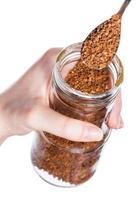 spoon scoops up coffee crystals from glass jar photo