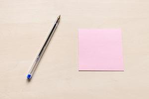 pink sheet of note paper and blue pen on board photo