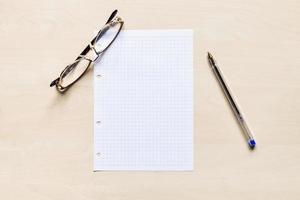 eyeglasses, pen and blank sheet of squared paper photo