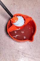 top view of squeezing mop in red bucket at home photo