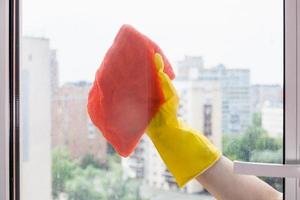 cleaning glass of home window by orange rag photo