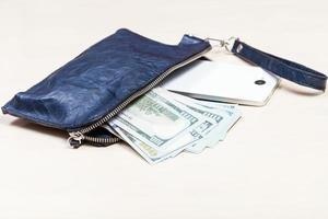 purse bag with phone and US dollars on table photo