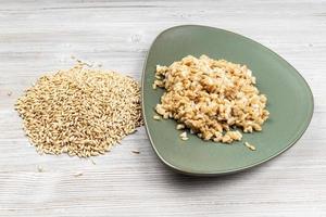 raw whole oat grains and boiled porridge on plate photo