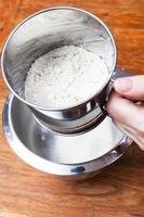 sifting the flour through steel sifter into bowl photo