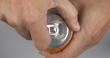 la mano abre una lata de cerveza de metal naranja
