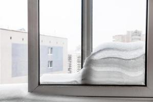 window with snowdrift between frames in winter photo