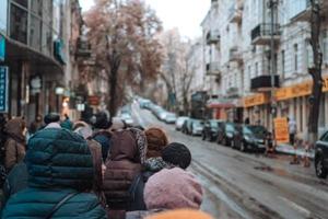 Many unidentified people are waiting for city transport at the bus stop photo