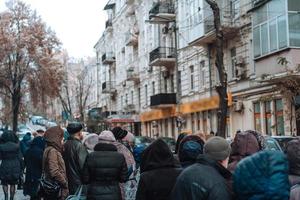 Many unidentified people are waiting for city transport at the bus stop photo