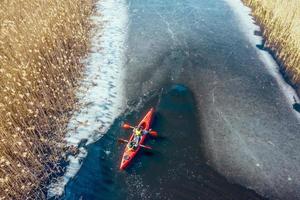 two athletic man floats on a red boat in river photo