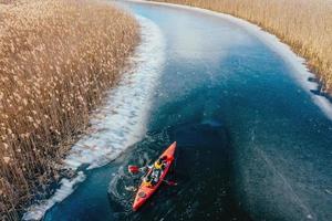 two athletic man floats on a red boat in river photo