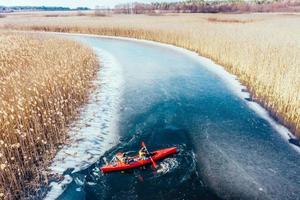 two athletic man floats on a red boat in river photo