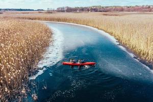 two athletic man floats on a red boat in river photo