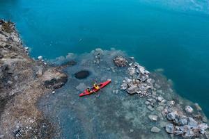 two athletic man floats on a red boat in river photo