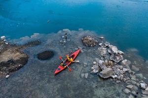 two athletic man floats on a red boat in river photo