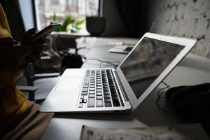 mujer joven sentada en la mesa de la oficina con la computadora portátil. foto