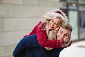 Young handsome guy giving girlfirend piggyback ride photo