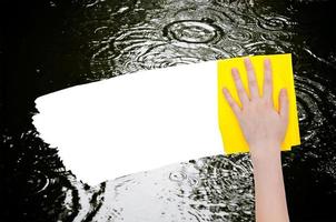 hand deletes rainy puddle by yellow rag photo