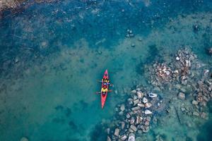 two athletic man floats on a red boat in river photo