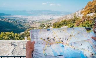 sosteniendo el mapa en las manos, vista de la ciudad en el fondo foto