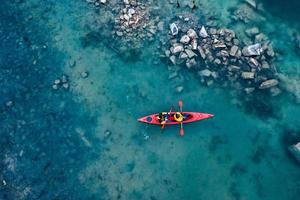 two athletic man floats on a red boat in river photo