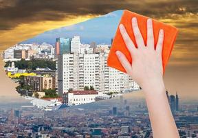 hand deletes smog in city by orange cloth photo