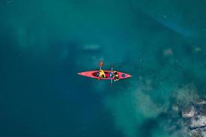 two athletic man floats on a red boat in river photo