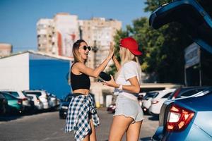 dos chicas jóvenes con gafas de sol posando para la cámara en el aparcamiento. foto