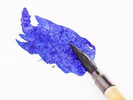 blue colored tip of paintbrush in blot close up photo
