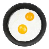 top view of fried eggs in black round pan isolated photo