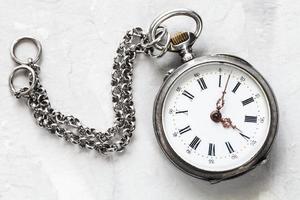 retro pocket watch with chain on white plaster photo
