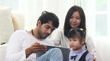 asiatisk familjer är Lycklig på semester på Hem. föräldrar lära deras döttrar till studie uppkopplad med en läsplatta. ökande Kompetens och inlärning utveckling i barndom video