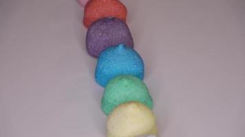 caramelos de malvavisco muy coloridos sobre un fondo blanco girando en círculo - imágenes en bucle.