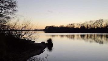 romantischer Blick auf einen See bei Sonnenuntergang mit spiegelnder Wasseroberfläche video