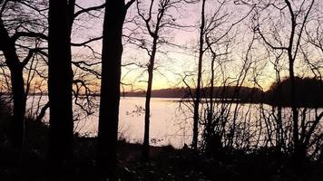 vista romântica em um lago durante o pôr do sol com uma superfície de água reflexiva video