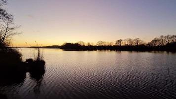 vista romântica em um lago durante o pôr do sol com uma superfície de água reflexiva video