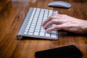 Left Female hand on computer keyboard with mouse photo