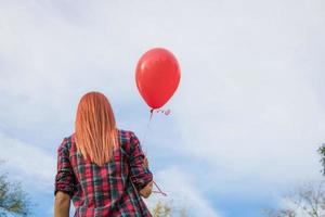 Rear view of woman with red balloon against the sky. photo