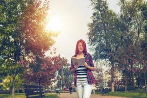 Beautiful girl with a book walking through the park. photo